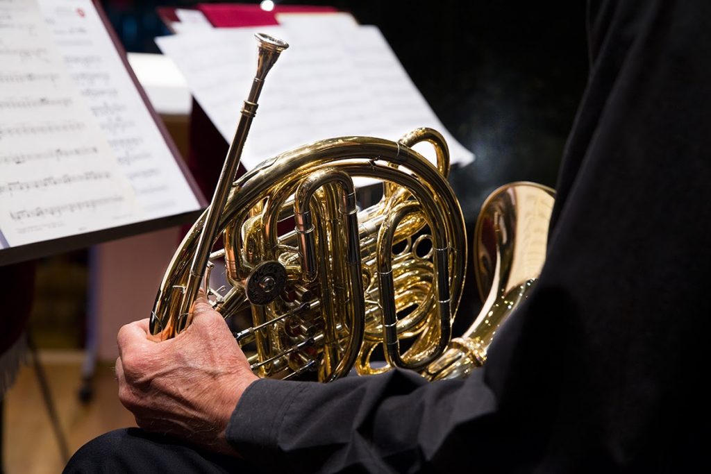 A horn rests on a musicians lap.