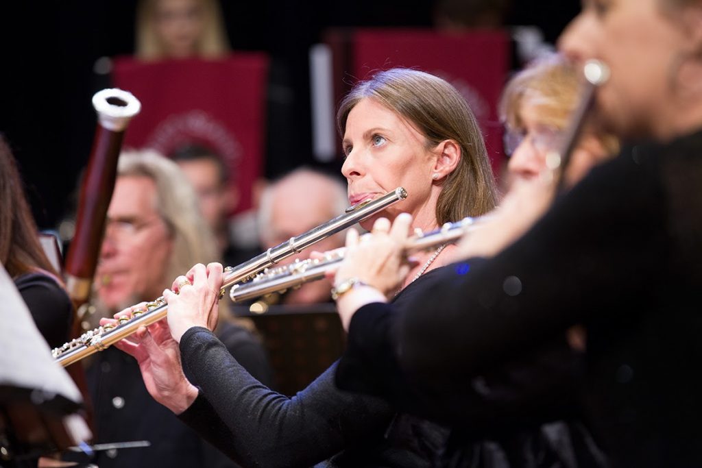 At a concert, a row of musicians play the flute